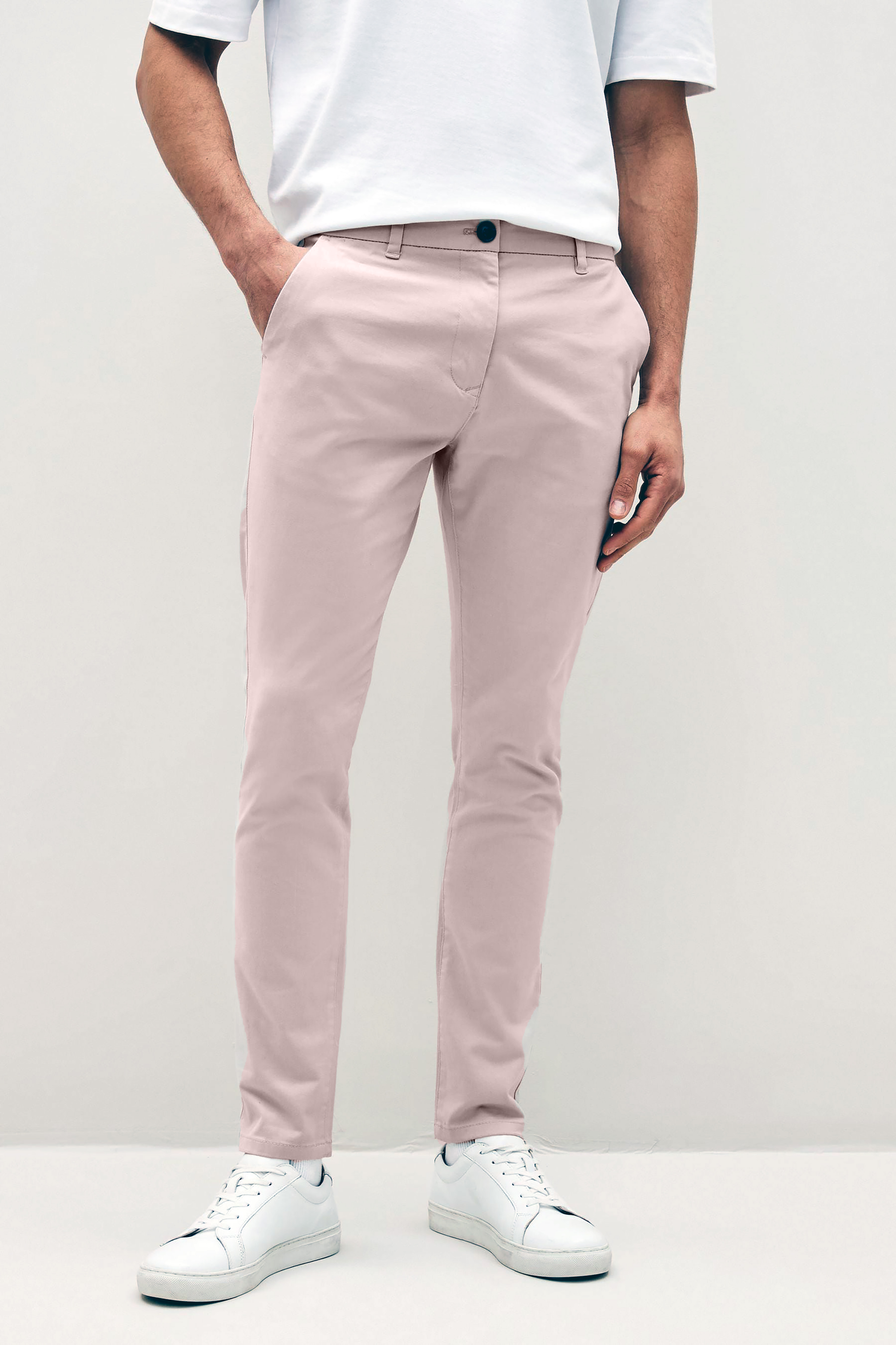 Mens pale pink chinos with front slanted pockets, jetted back pockets. zip fly fastening and brown horne buttons on the waistband and back pockets, the fit is a slim fit, this is worn with a white tee and white unbranded trainers