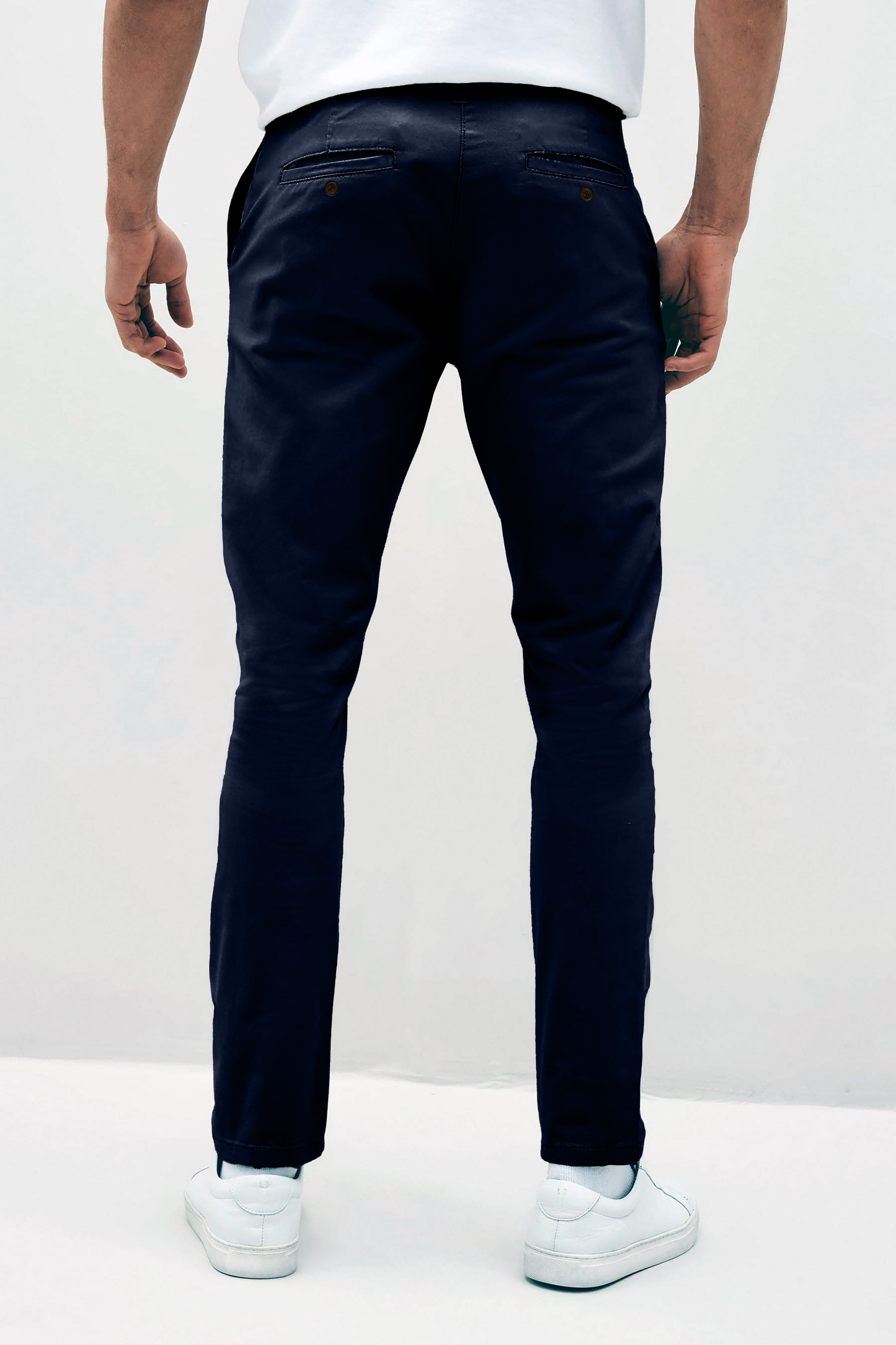 Mens Navy chinos with front slanted pockets, jetted back pockets. zip fly fastening and brown horne buttons on the waistband and back pockets, the fit is a slim fit, this is worn with a white tee and white unbranded trainers