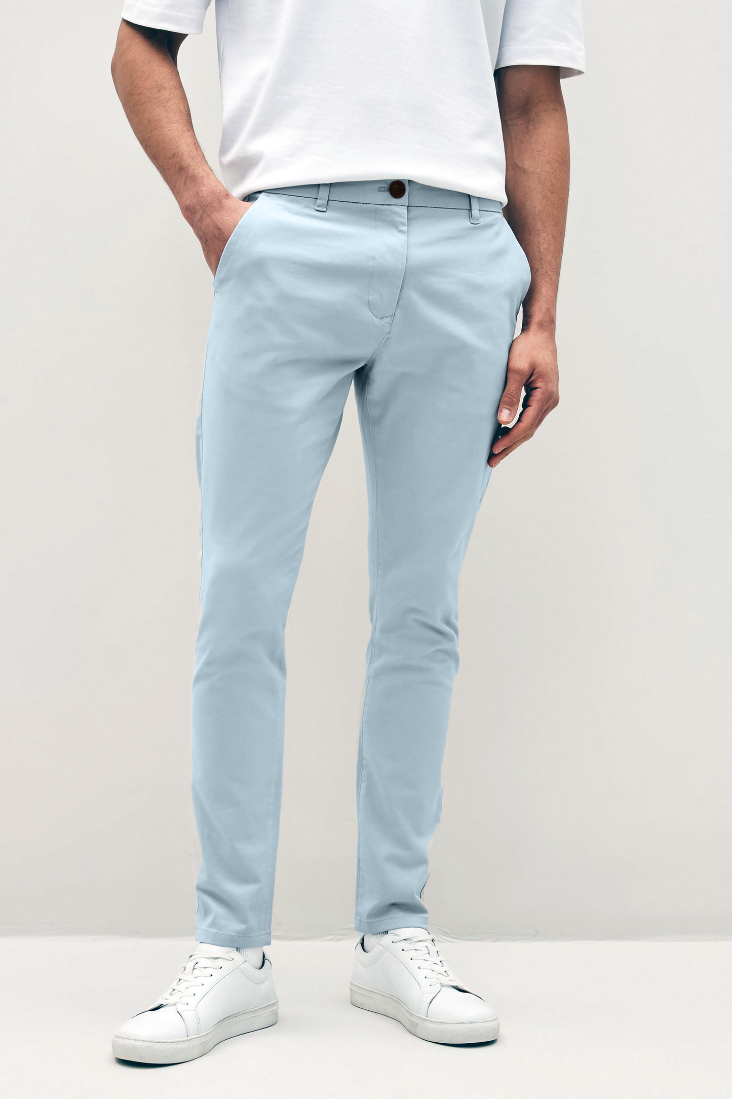 Mens sky Blue chinos with front slanted pockets, jetted back pockets. zip fly fastening and brown horne buttons on the waistband and back pockets, the fit is a slim fit, this is worn with a white tee and white unbranded trainers